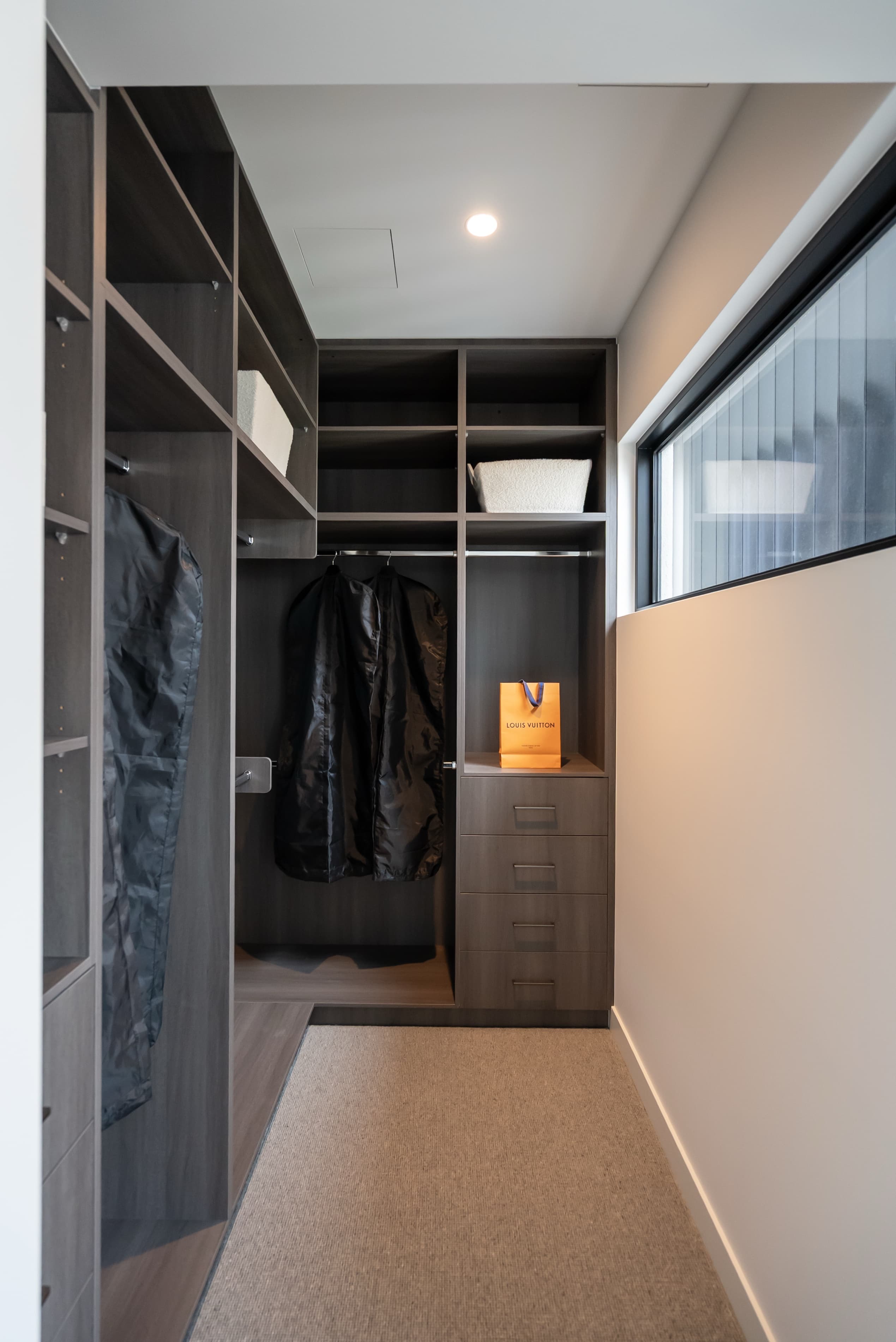 Walk-in closet with dark timber shelving and drawers