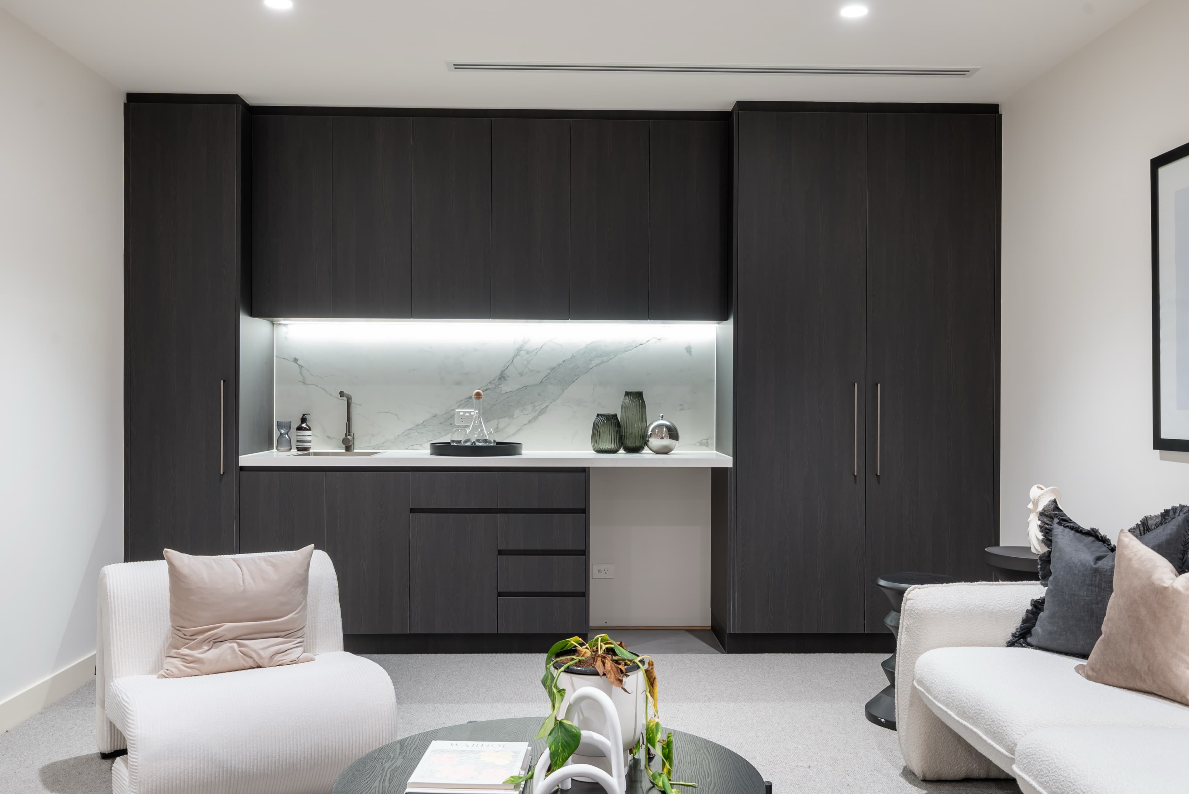 Dark timber built-in cabinetry with marble splashback wet bar
