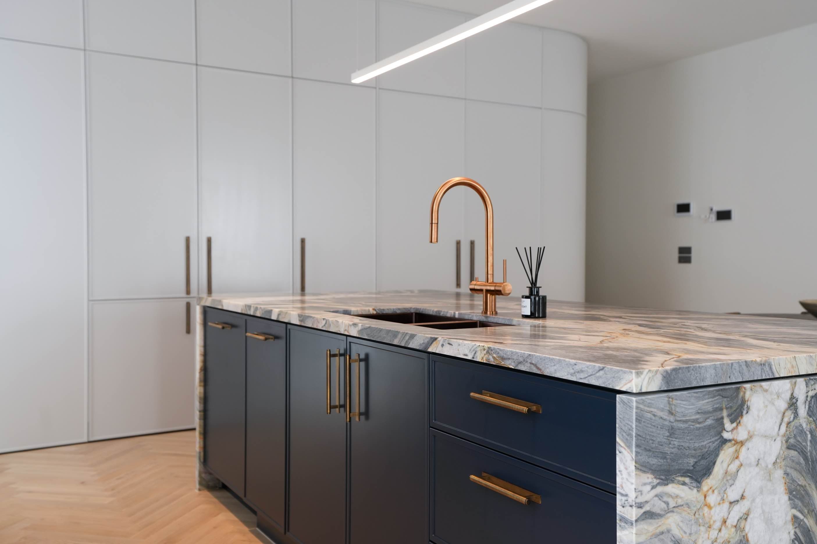Navy kitchen island with marble countertop and copper tapware